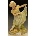 A German porcelain model, of a young girl dancer, playing with her skirt by a rose bush,