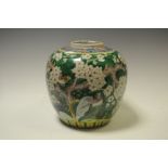 A Chinese ginger jar, painted with white blossom trees, birds of prey and rockery on a green ground,