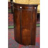 A George IV mahogany bow fronted wall hanging corner cupboard, c.