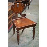 A mahogany hall chair, shaped back carved with crest, squared seat, turned legs.