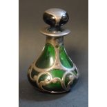 An Art Nouveau scent bottle, green bottle encased within scrolling pewter mounts,