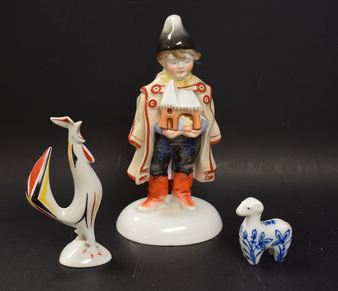 A Herend figure of a boy holding a nativity scene, wearing a pointed hat and cape, domed base,