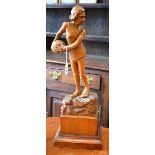 An Art Deco oak carving, of a young girl holding a beach ball, she stands, on a rocky outcrop,