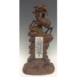 A large Black Forest table thermometer, carved as a deer atop a rocky outcrop,