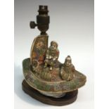 A Japanese satsuma table lamp, modelled as figures onboard a ship, wooden base, 23cm wide,