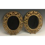 A pair of early 20th century giltwood and gesso oval looking glasses, pierced fruiting vine borders,