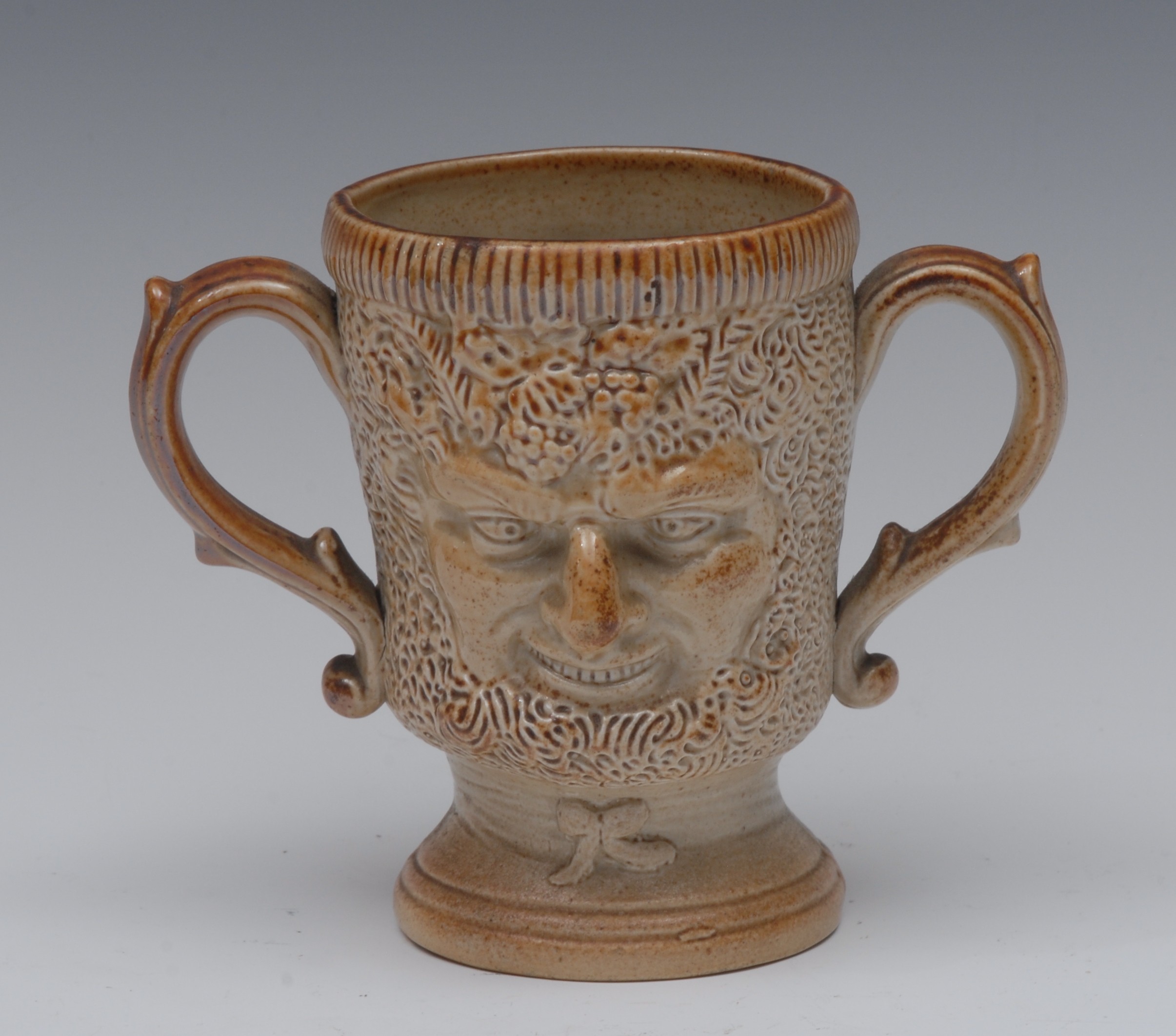 A 19th century brown salt glazed stoneware Bacchus mask two-handled mug, relief moulded,