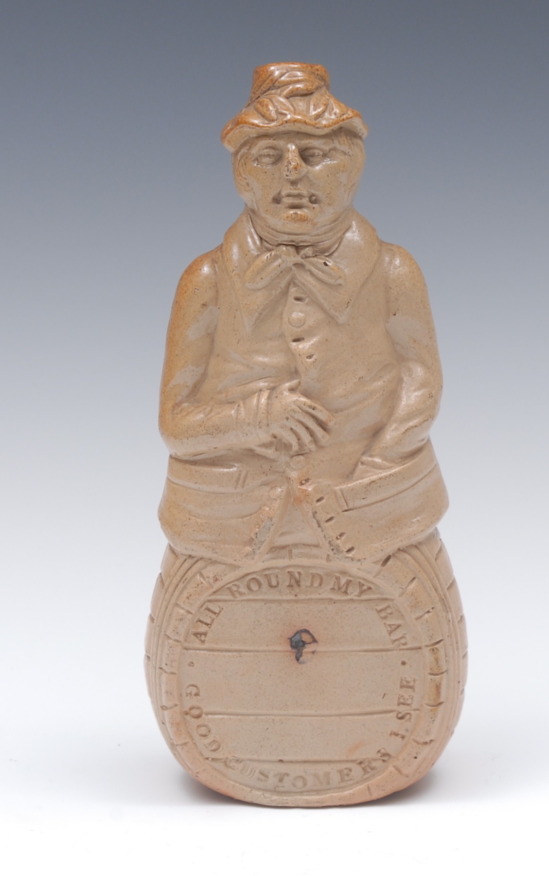 A 19th century brown salt glazed stoneware figural flask, of a man seated on a barrel,