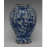 An 18th century Dutch Delft baluster vase, decorated in blue with flowerheads, tress and rockwork,