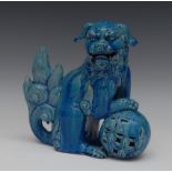 A Chinese turquoise monochrome temple lion, seated to the left, its paw on a ball, 24cm high,