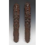 A pair of 17th century oak figural pilasters, each carved with a bearded face above flowers,