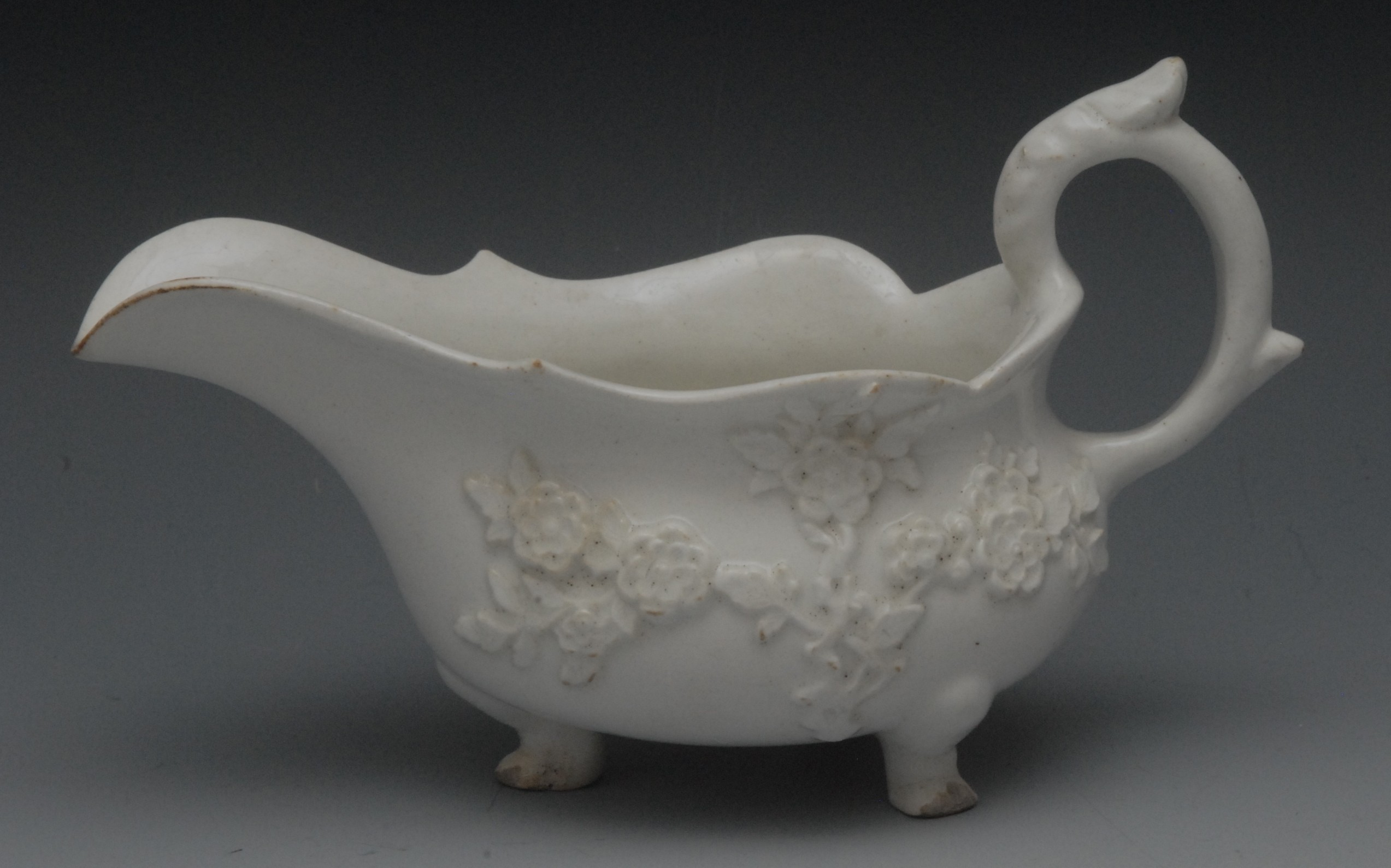 A Bow Blanc de Chine sauce boat, in relief with blossoming prunus, three pad feet, scroll handle,