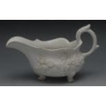 A Bow Blanc de Chine sauce boat, in relief with blossoming prunus, three pad feet, scroll handle,