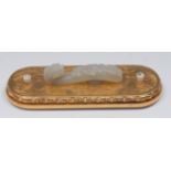 A Chinese pale celadon jade ruyi shaped buckle, carved with a stylised dragon mask and scrolls,