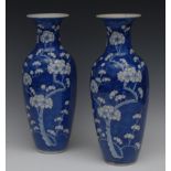 A pair of Chinese slender ovoid vases, decorated with blossoming prunus branches, on a blue ground,