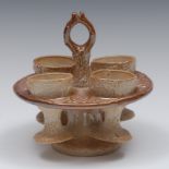 A 19th century brown salt glazed stoneware four-egg cup stand and cups, rustic posted loop handle,