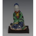 A Chinese figure, Guanyin, seated, coloured in green, blue and yellow, 10cm high,