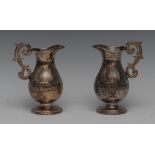 A pair of South American cast silver oil and vinegar ewers,