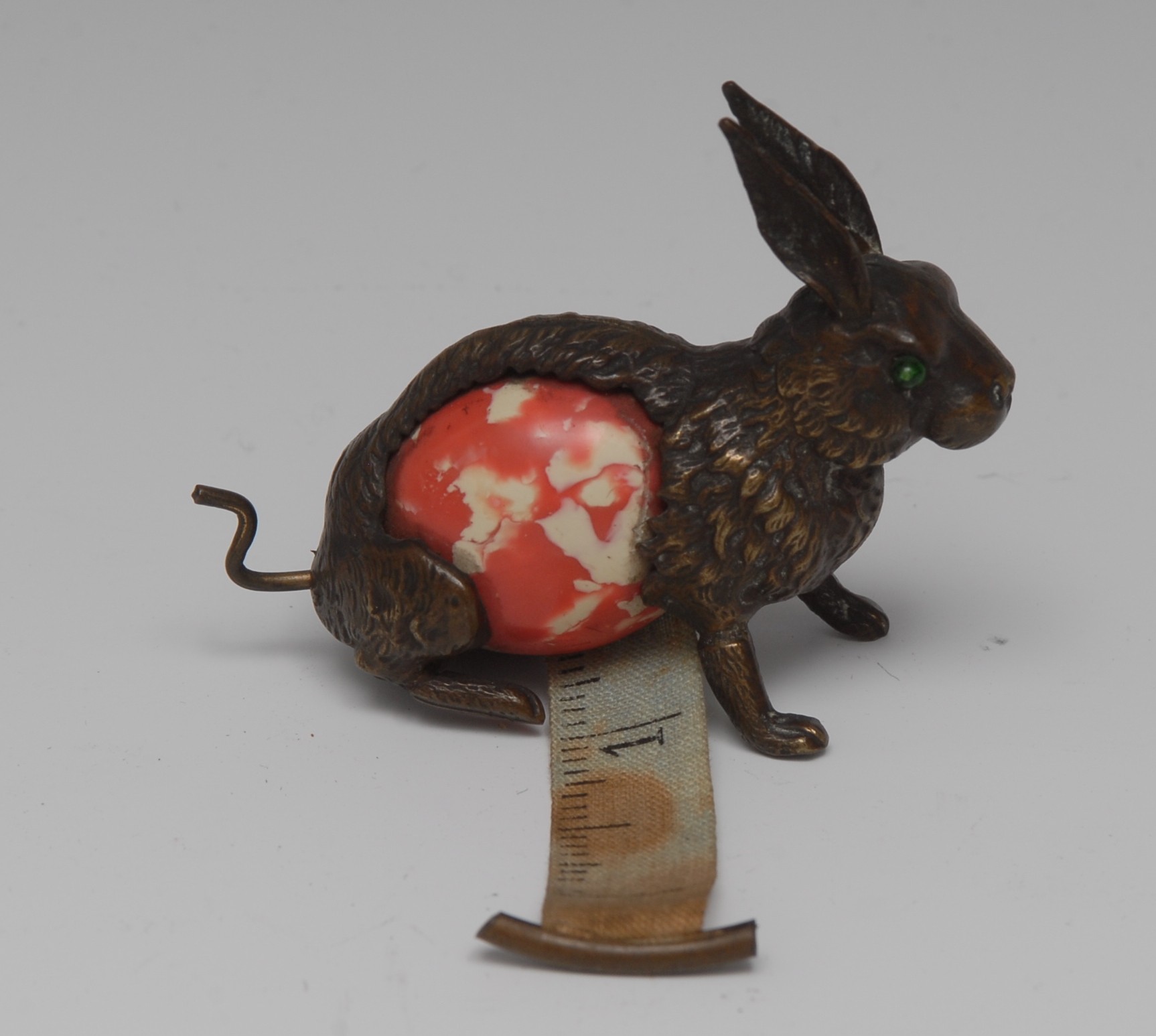 A 19t century novelty bronzed tape measure holder, in the form of a hare, green glass eyes,