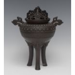 A Japanese dark patinated bronze tripod koro and cover, in the Archaic taste, cast with scrolls,