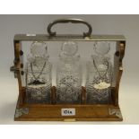 A late 19th century oak three bottle tantalus, retailed by Rowell & Harris, Oxford,