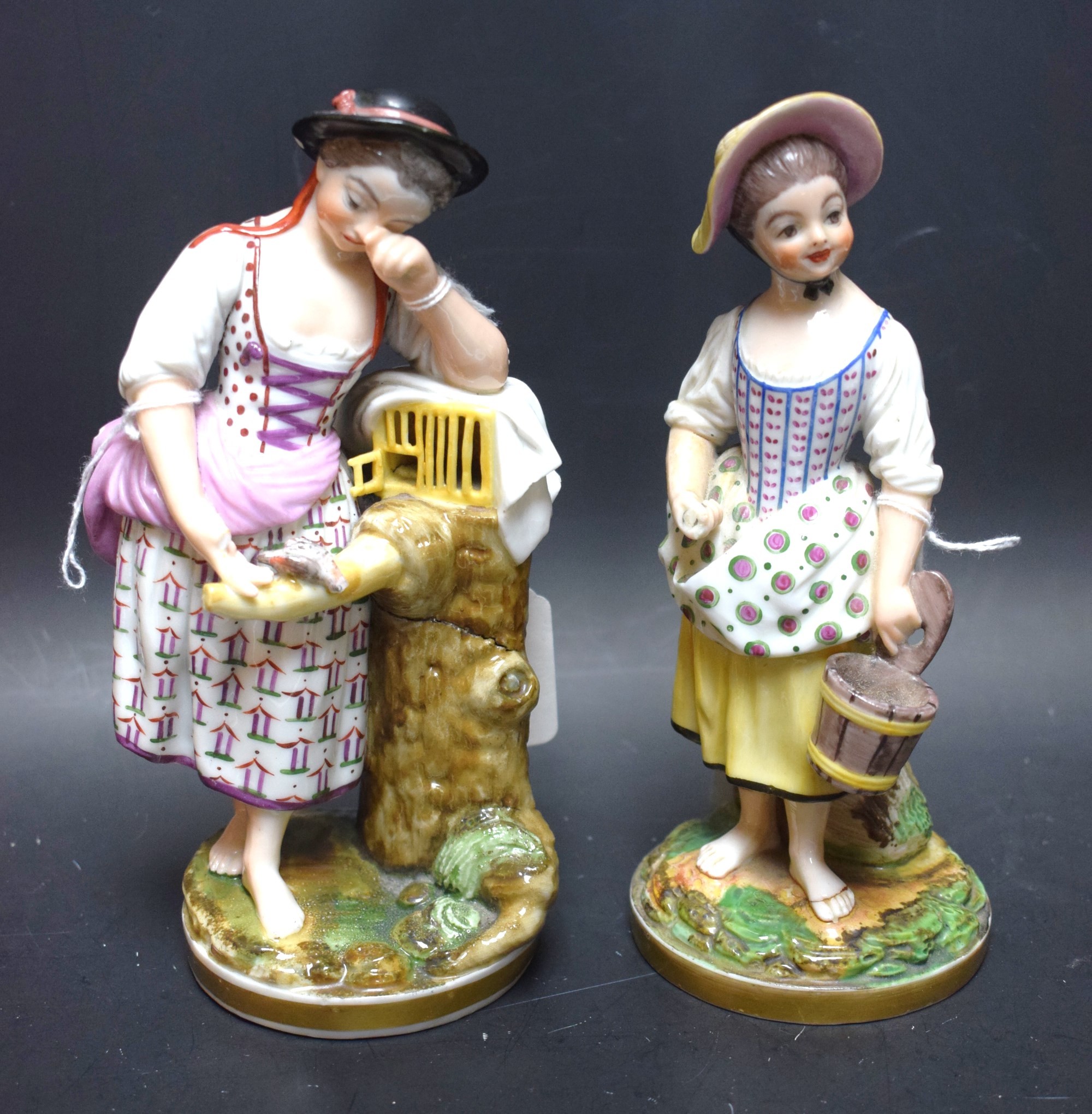 A pair of porcelain figures, of ladies, one with a pail, the other with dove, in colours,