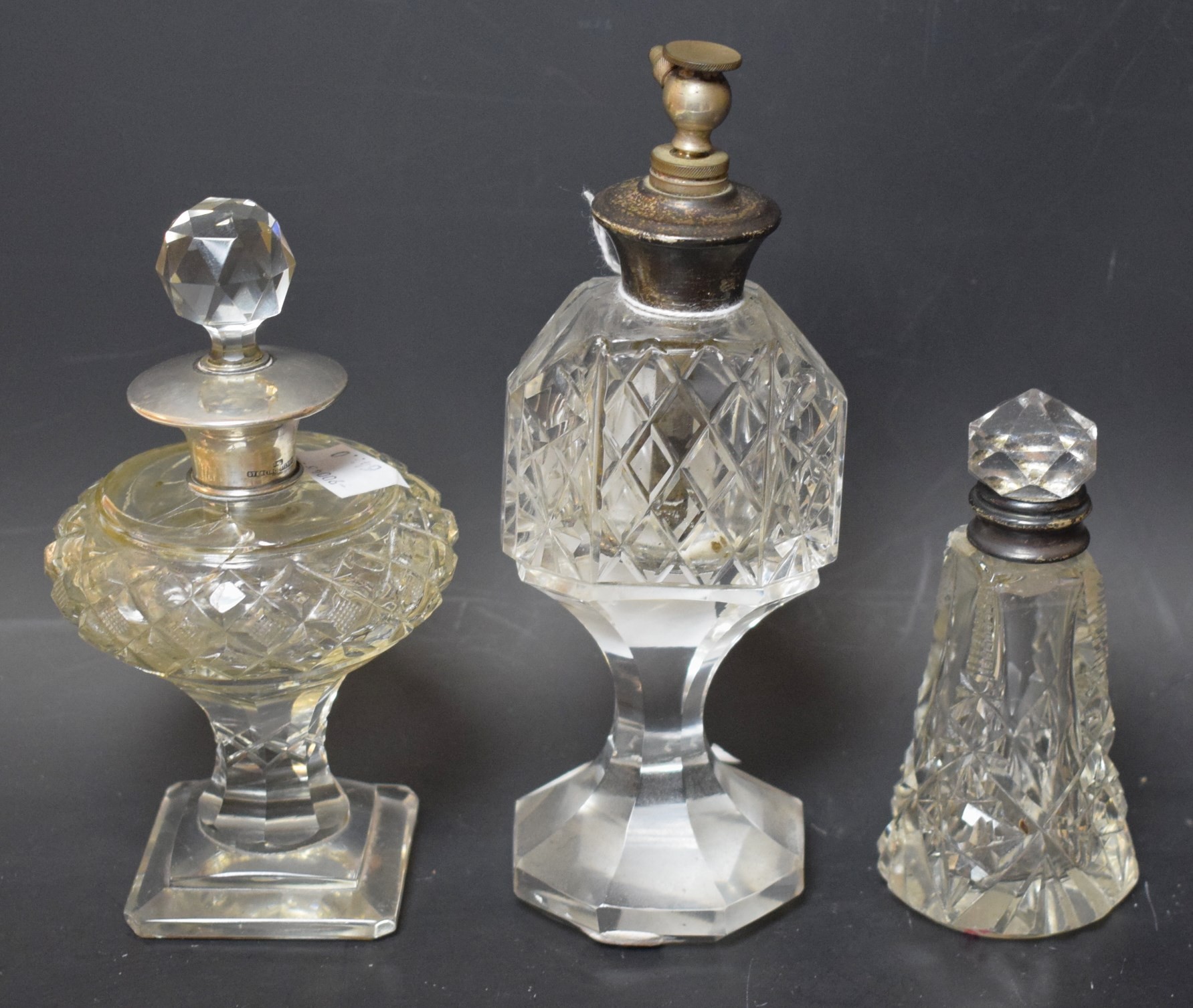 Three cut glass scent bottles with silver tops