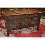 An 18th century oak blanket chest, three paneled top and front, the front panels heavily carved,