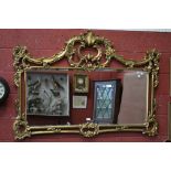 A large gilt framed wall mirror, scrolling foliate pediment nd frame, rectangular bevel edge plate.