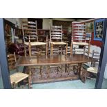 An oak trestle table; eight oak rush seated ladder back chairs,