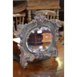 A 19th century Italian cartouche shaped looking glass, carved,