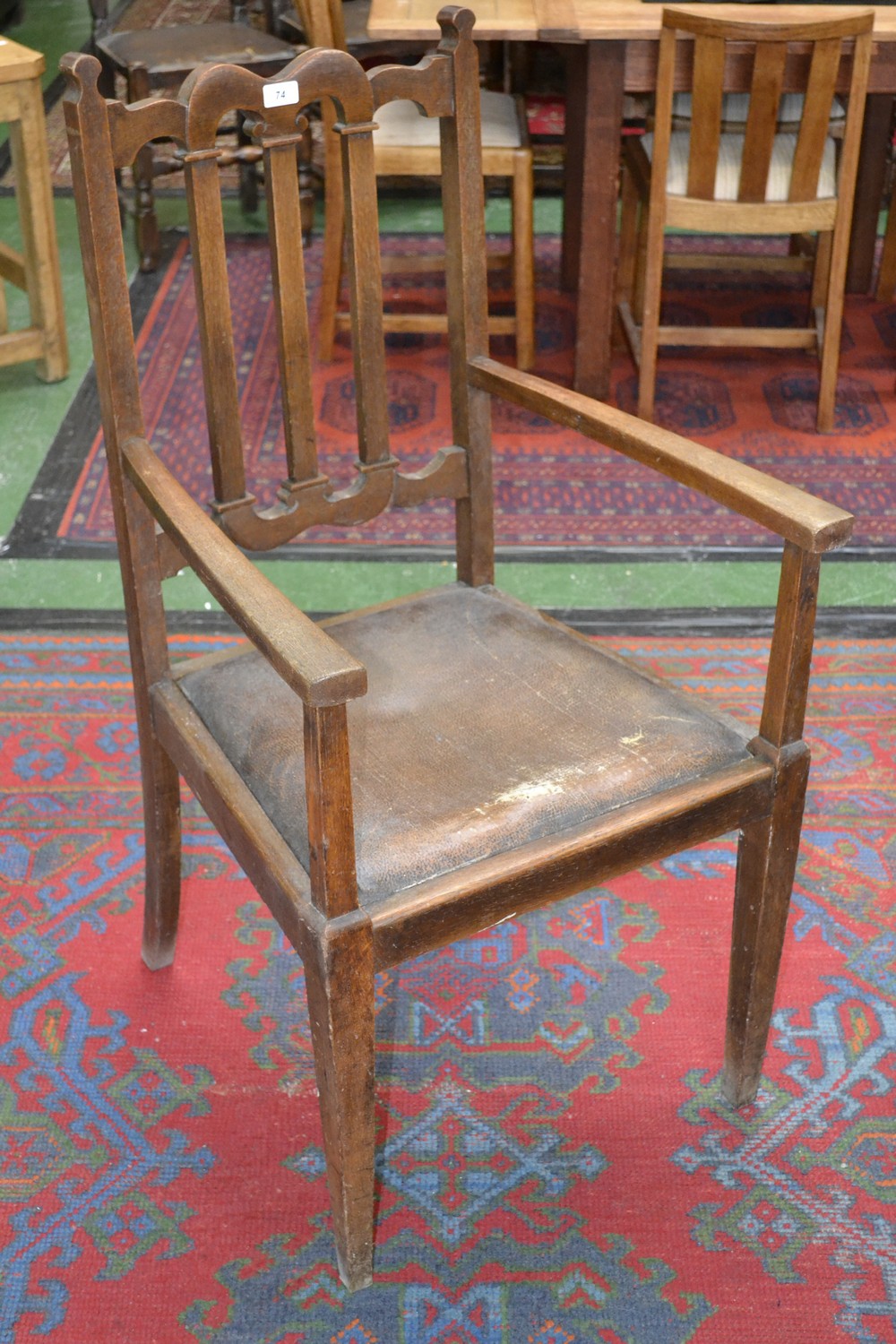 An Arts and Crafts oak carver chair, shaped top rail, drop in seat, tapering square supports.