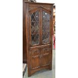 A contemporary oak floor standing corner cupboard, two lead glazed doors to top,