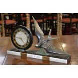 A 1930's Art Deco mantel clock, having a circular face beside a swooping swallow on a marble base.