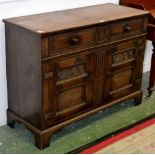 A late 20th century oak sideboard, oversaling top above two single drawers over two cupboards,