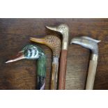 A walking cane with handle as a ducks head; two others,