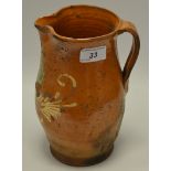 A French slipware jug, applied in white with leafy scrolls, 22cm high, c.