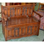 An Old Charm open arm settle, carved panel back, hinged cover to seat enclosing storage.