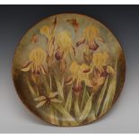 An Art Pottery circular charger, printed and painted with yellow irises, moths and dragonfly,