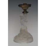 A French Art Deco pressed glass table lamp, moulded as a scatilly clad maiden crouching a rocks,