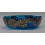 An Art Nouveau blue glass circular bowl, applied in gilt with hineysuckle flowerheads, 24.