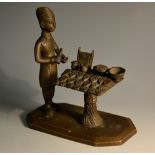 An Indian bronze model, of a street peddler, he stands preparing a selection of betel nuts,