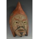 A Japanese hardwood noh mask, carved as a man wearing a pointed red cap,