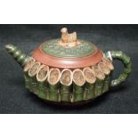 A Chinese Yixing terracotta teapot and cover, applied with sections of bamboo,