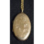 A 9ct gold oval locket, 12.7g gross, suspended from a yellow metal chain, 16.