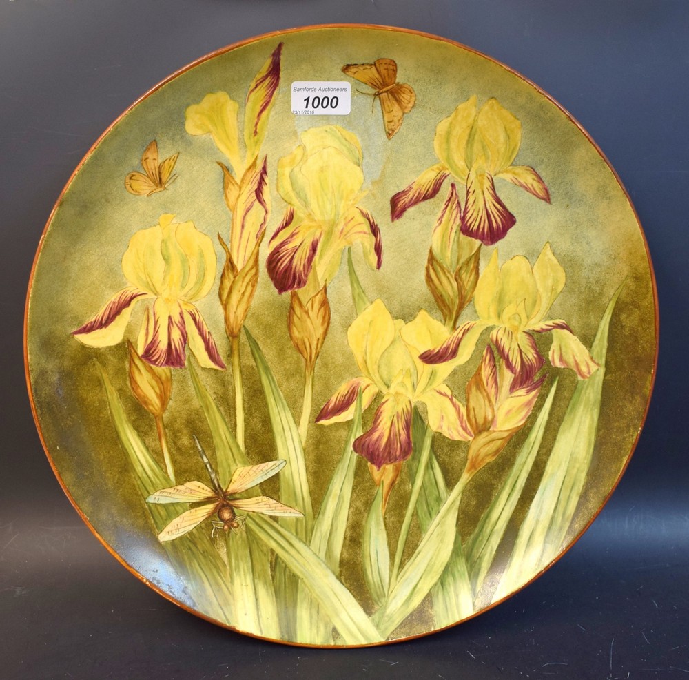 An Art Pottery circular charger, printed and painted with yellow irises, moths and dragonfly,