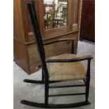 A rush seated ladder back rocking armchair, ebonised black ash?