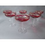 A collection of 12 etched cranberry glass champagne glasses with early twist stems and gold rim