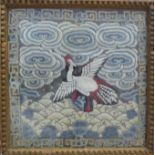 A C19th Chinese silk embroided emblem with scrolling clouds with central bird on waves with