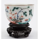 A Japanese Kakiemon teabowl: painted with a pine tree, a banded hedge, floral sprays and foliage,